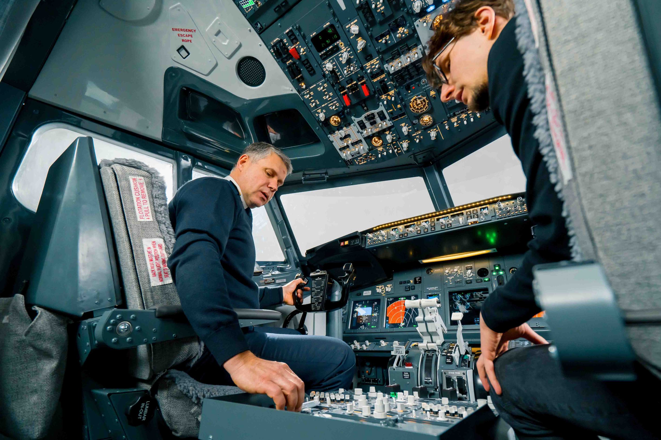 An experienced pilot instructs a young student before a training flight in the cockpit of aero simulator